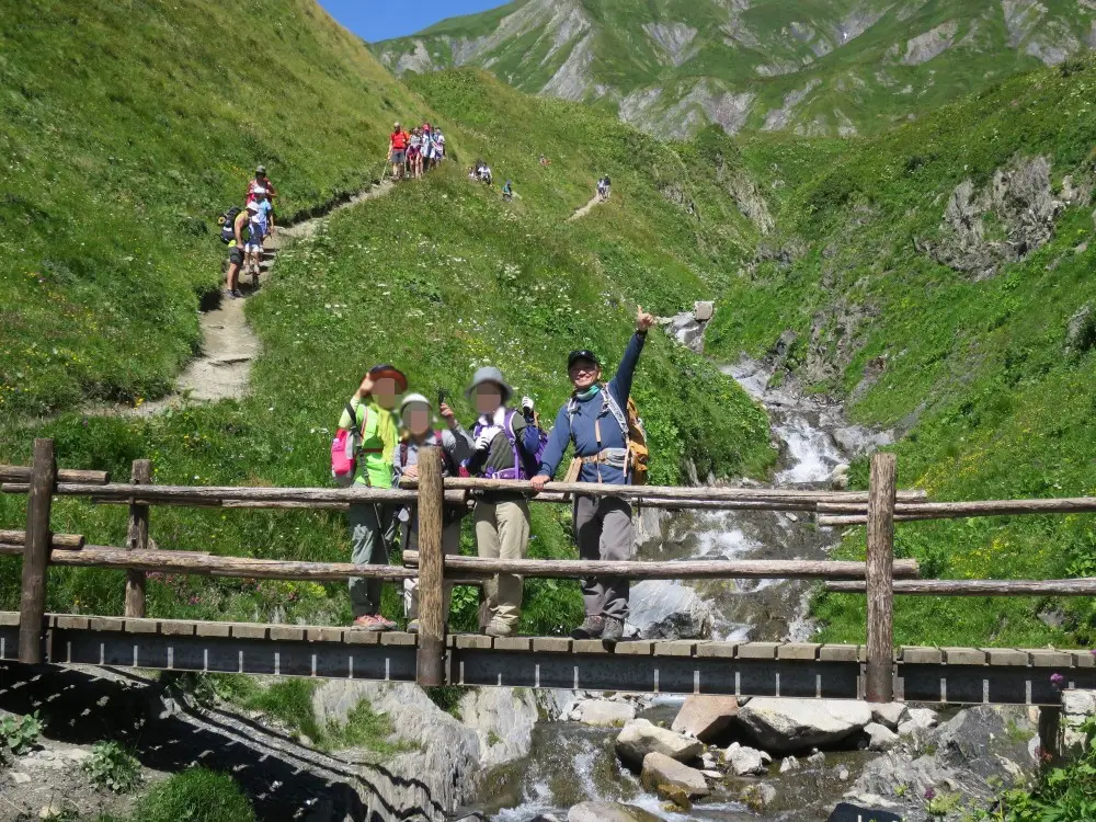 山道を歩くハイカーたちと、橋の上で笑顔を見せる人々。