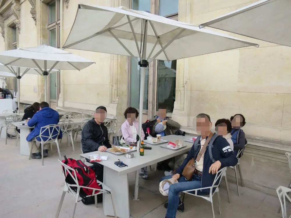ルーブル美術館のテラス席で、食事や休憩を楽しむ人々。