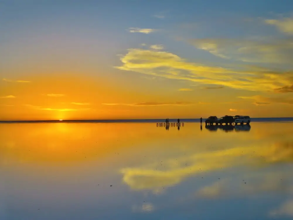 ウユニ塩湖の地平線に沈む夕日と、水面に映る光景。