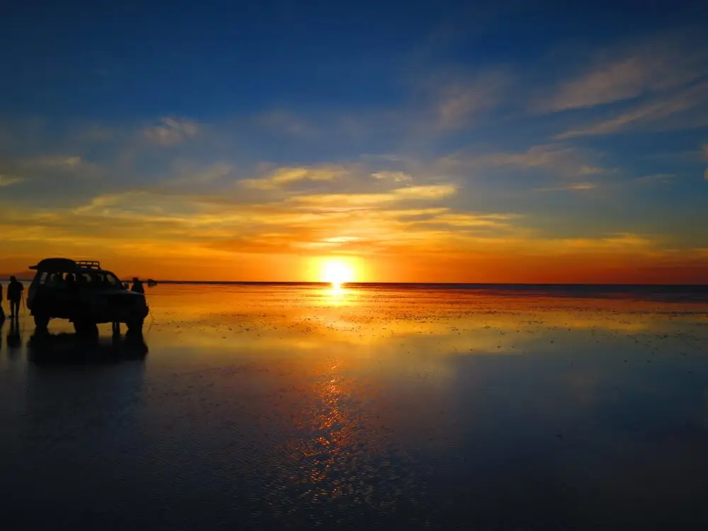 ウユニ塩湖の地平線に沈む夕陽と、水面に映る光の道