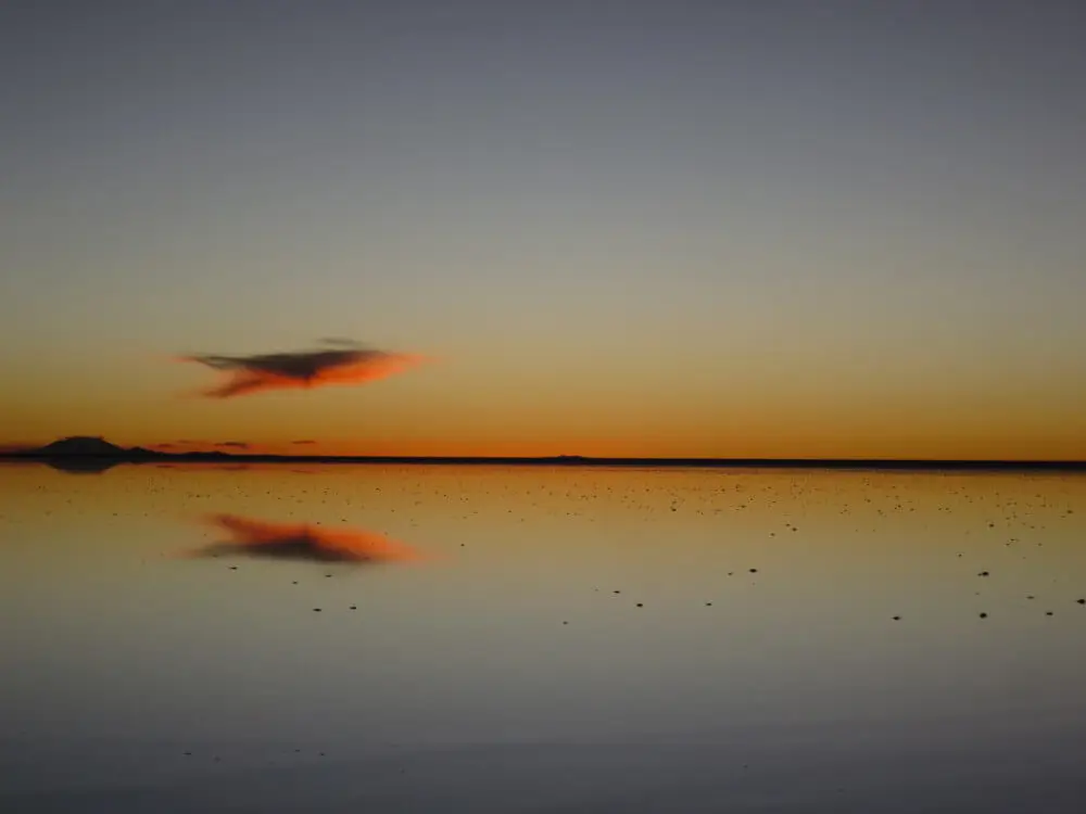 ウユニ塩湖に浮かぶ魚のような形の赤い雲とその反射