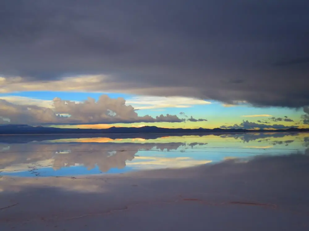 ウユニ塩湖の水面に夕焼けと雲が映し出された幻想的な光景