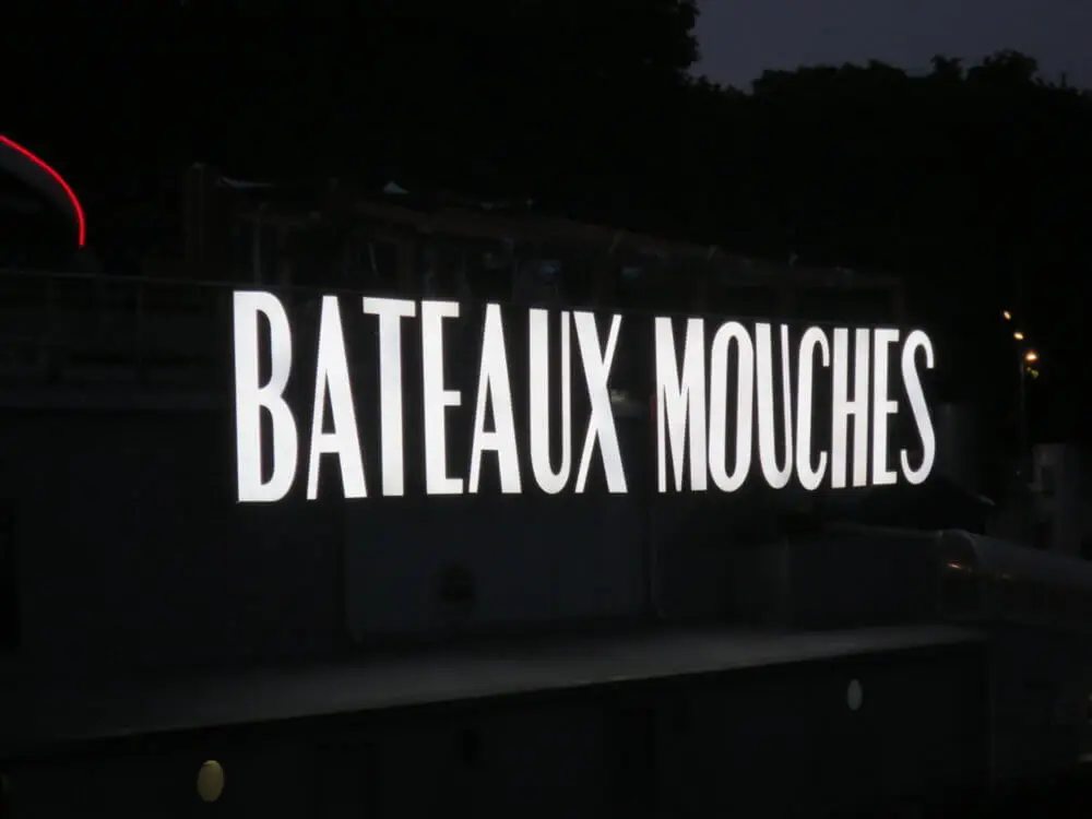 夜のセーヌ河に停泊する「BATEAUX MOUCHES」の文字が光る船名サイン。