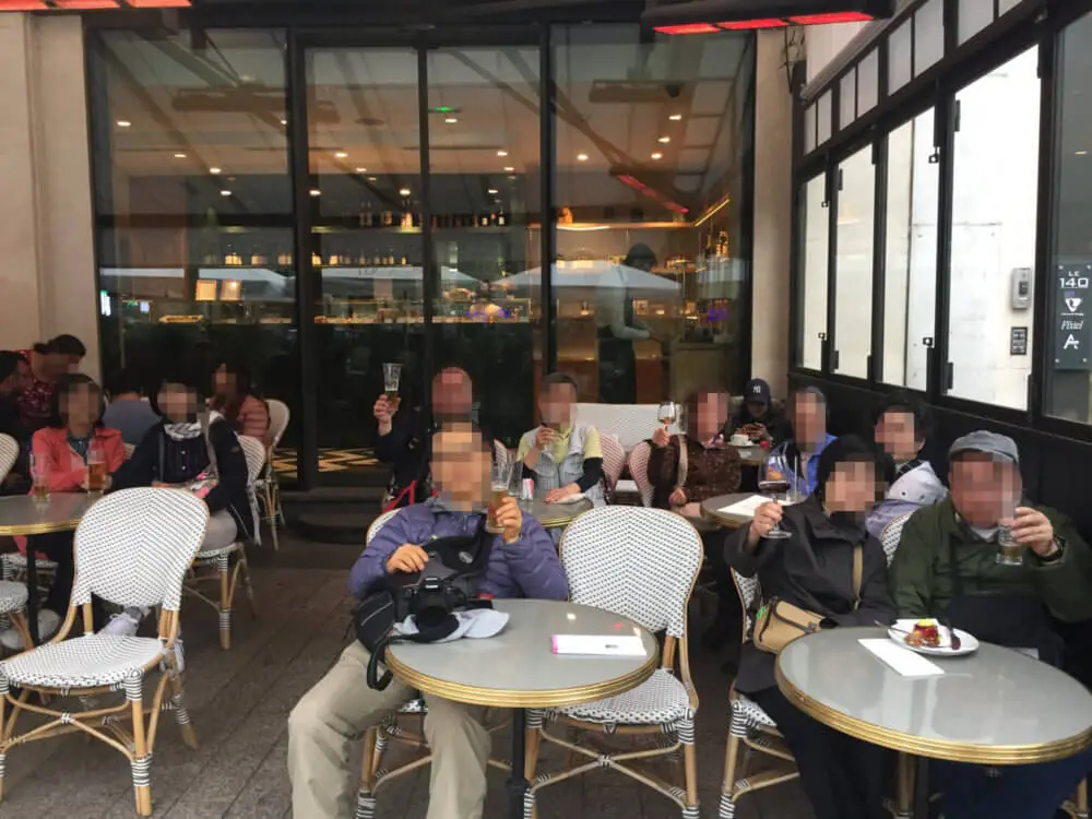 パリの街角のカフェテラスで飲み物を楽しむ旅行者たち