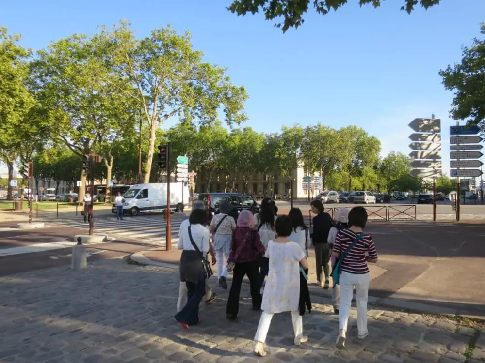 晴れた日にパリの交差点を渡る旅行者たち。