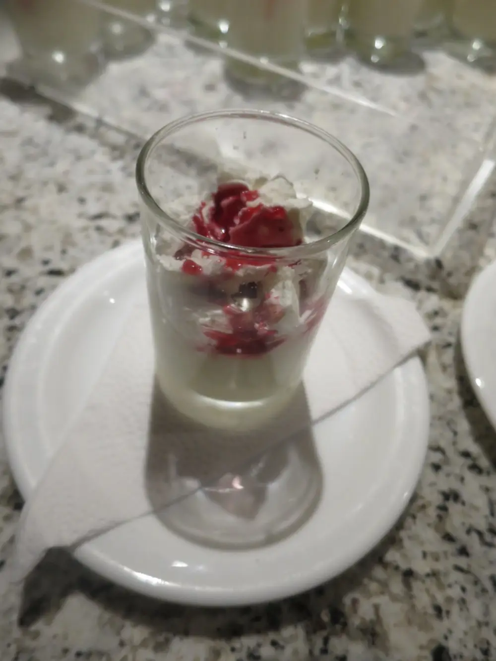 生クリームと赤いソースが添えられたグラスデザート