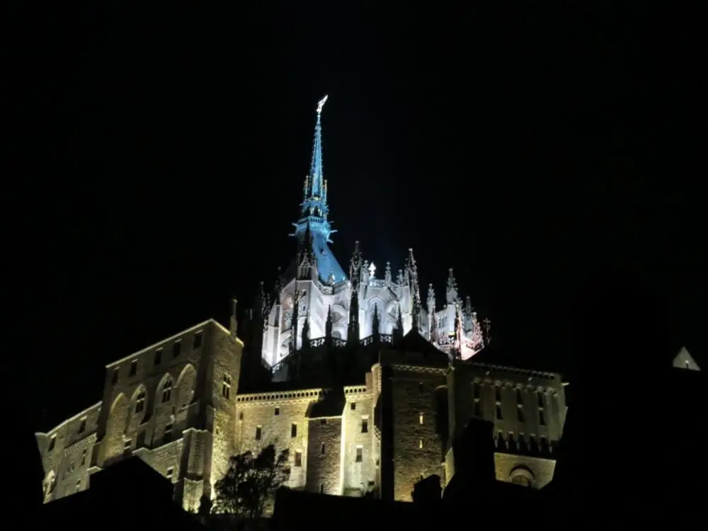 夜のモンサンミッシェル修道院、漆黒の空にそびえる姿を城壁から見上げる。
