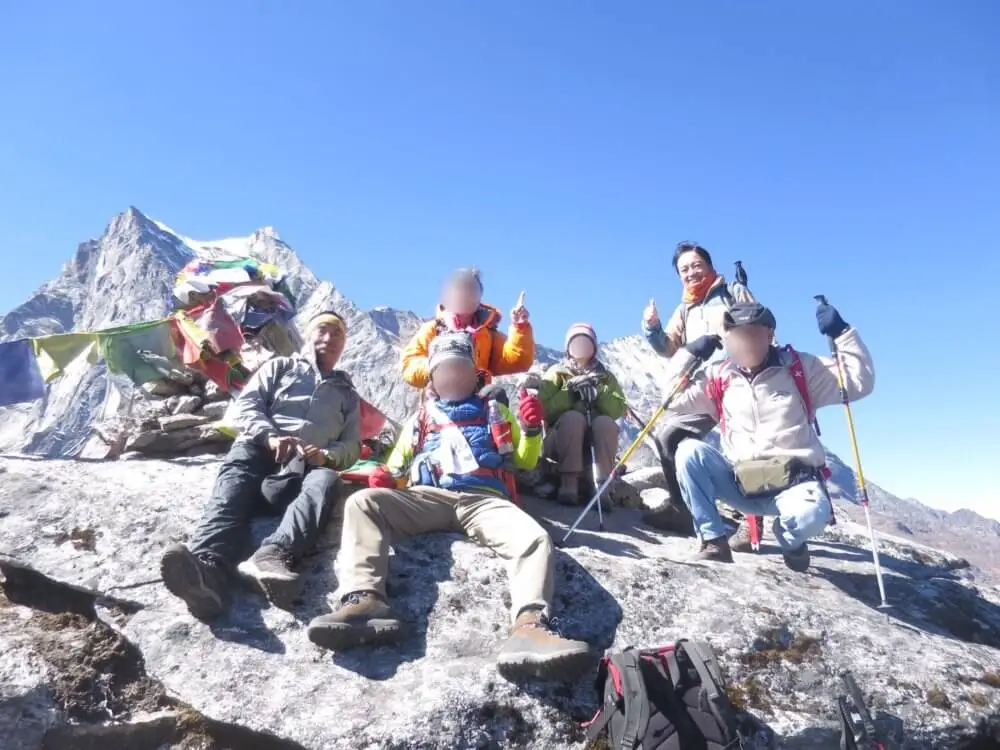 パラクピーク山頂のタルチョー前で喜びを表す登山者たち。