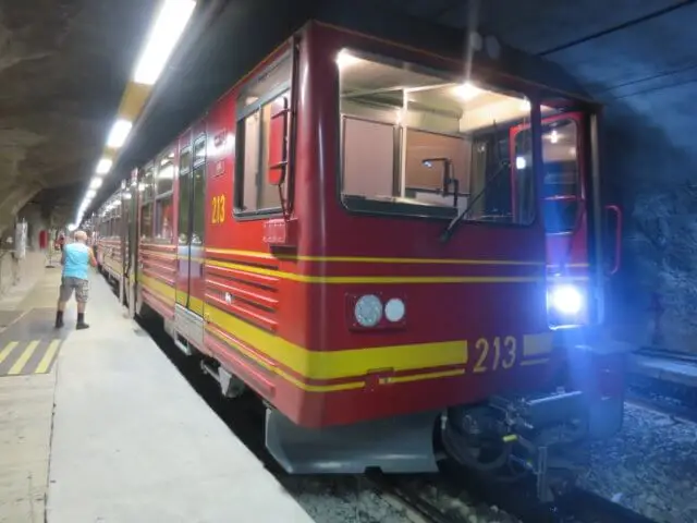 地下駅のプラットホームに停車する赤い登山電車213号。