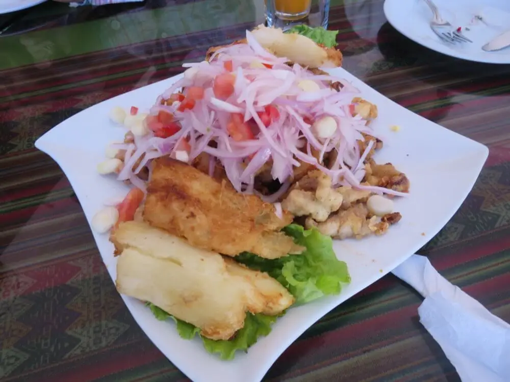 紫玉ねぎと魚介のペルー料理セビーチェ。揚げ物とコーンが添えられた一皿。
