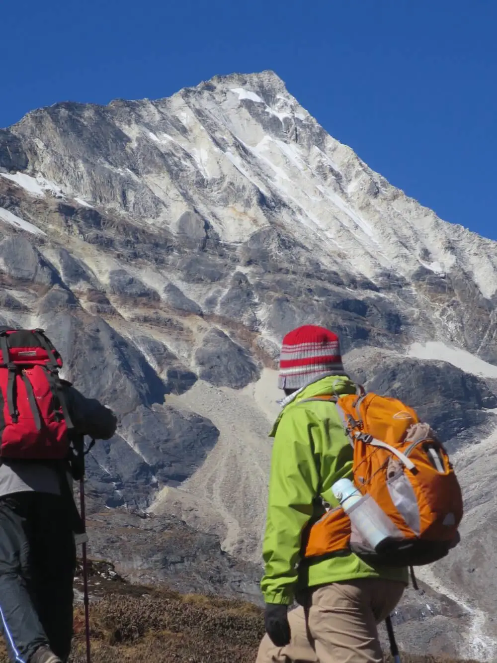 巨大な岩の壁がそびえる高峰コンデ・リを見上げる登山者。
