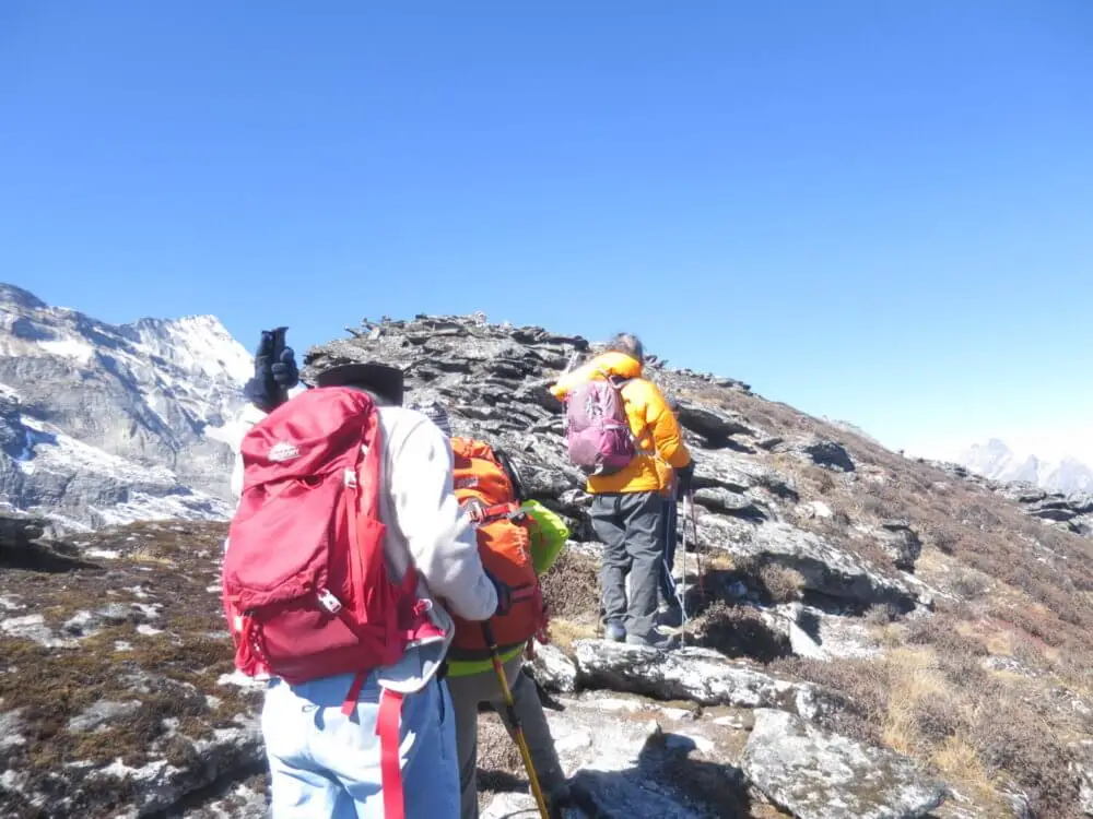 尾根の道を歩き、山頂のケルンを目指す登山者たち。