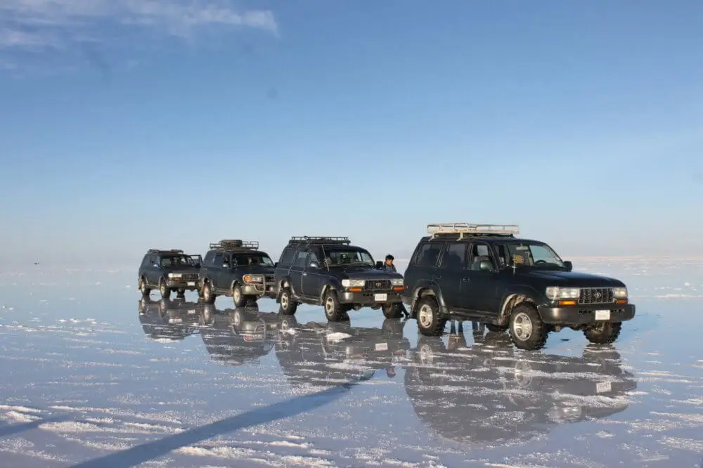 ウユニ塩湖の水面に並んで進む数台の4WD車