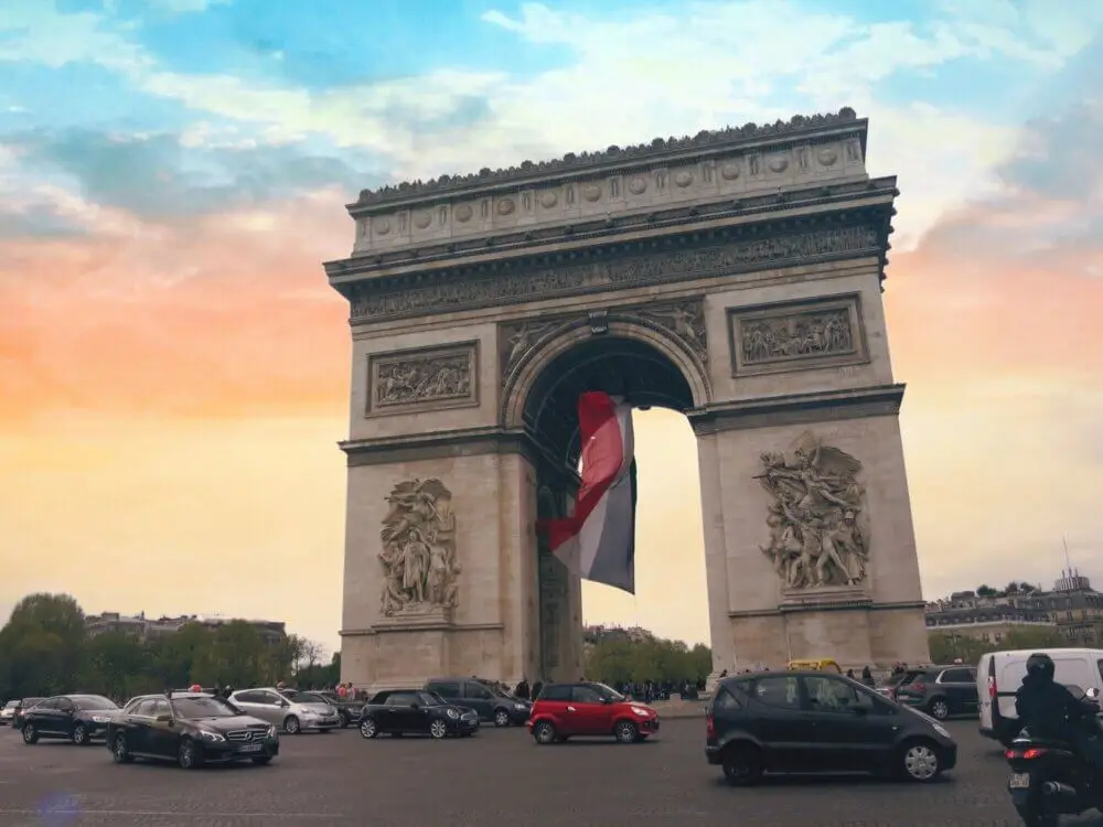 パリ凱旋門とフランス国旗、夕焼け空に映えるパリの象徴