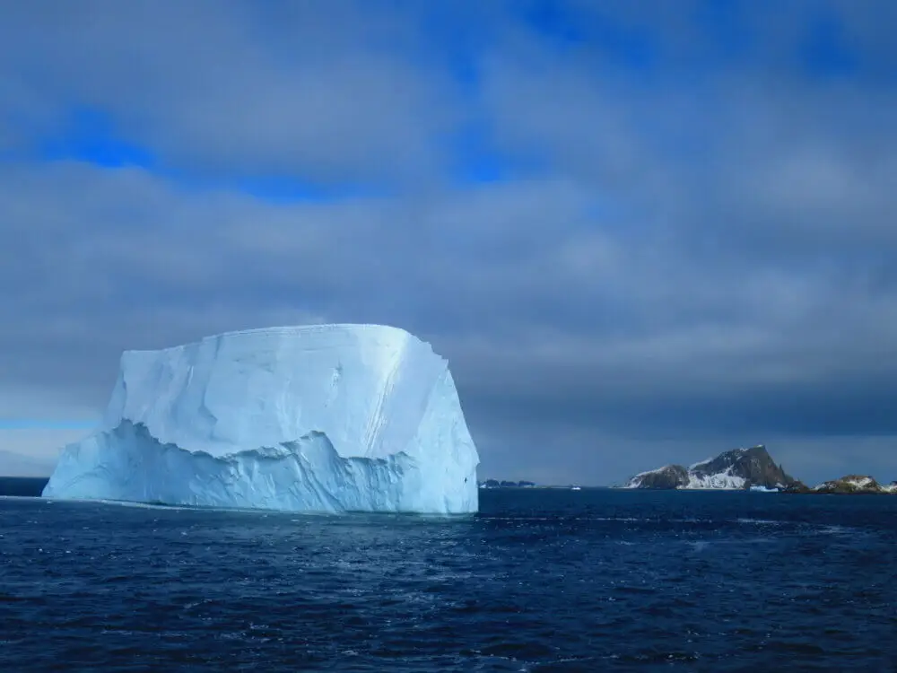 巨大な氷山が浮かぶ海、その先に南極大陸の山々が見える
