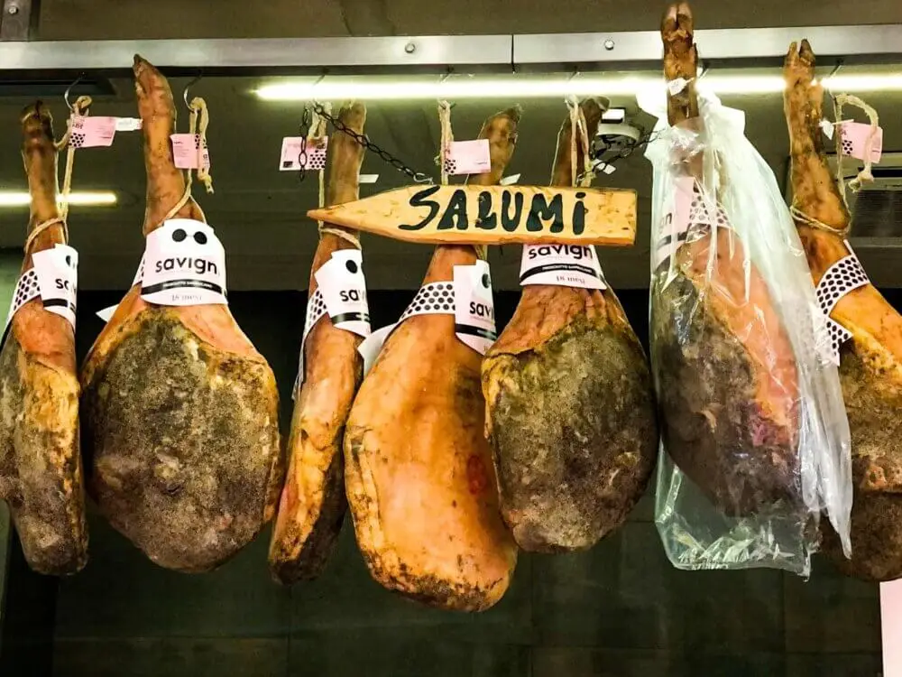 熟成された生ハムが多数吊るされたイタリアの食料品店