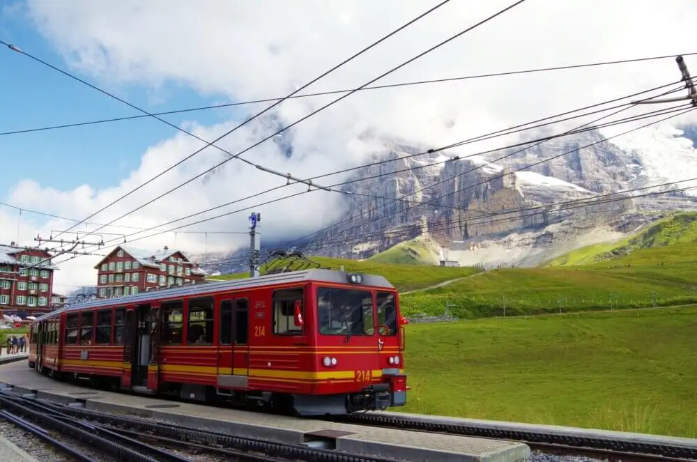 スイスの山岳駅に停車中の赤い列車と雲をまとった山々