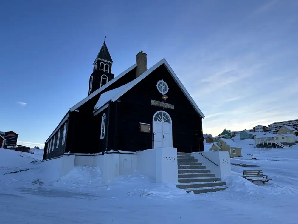 イルリサットの雪景色の中に建つ、黒い外壁のシオン教会。