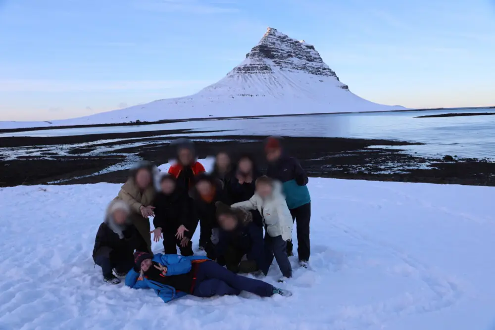 雪景色のアイスランド、キルケフェットル山を背景にポーズを取る人々。