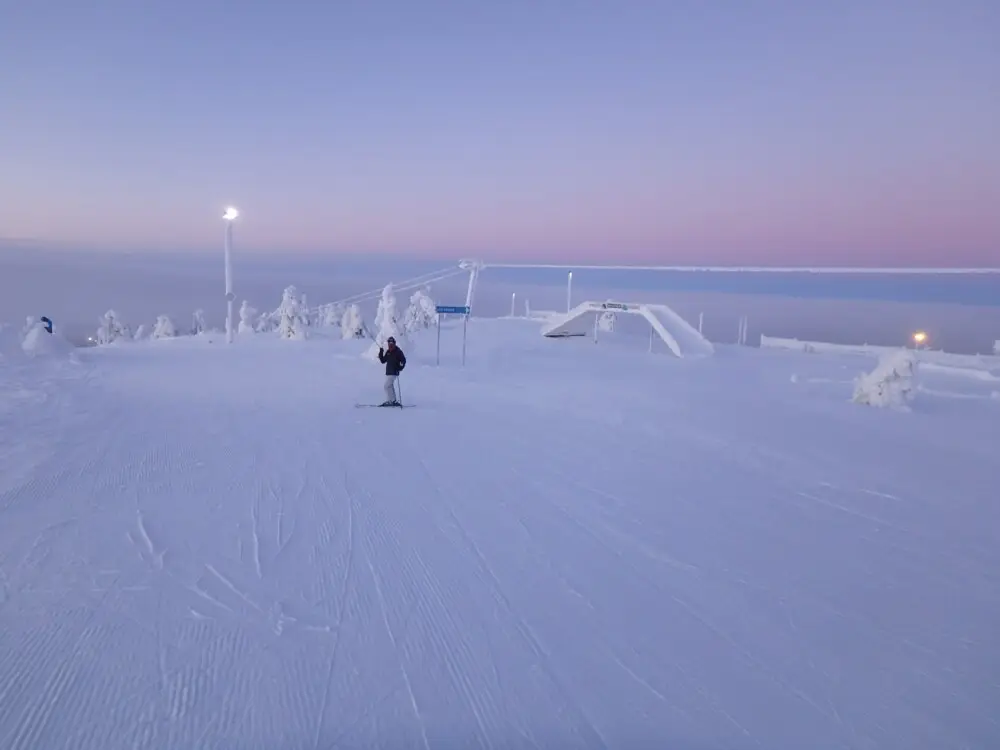夕暮れ時の雪山ゲレンデを滑るスキーヤーの姿