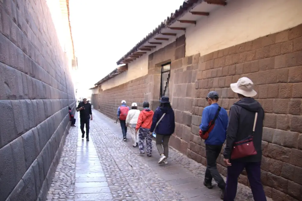 クスコの石畳の細い路地を歩く数人の旅行者の後姿