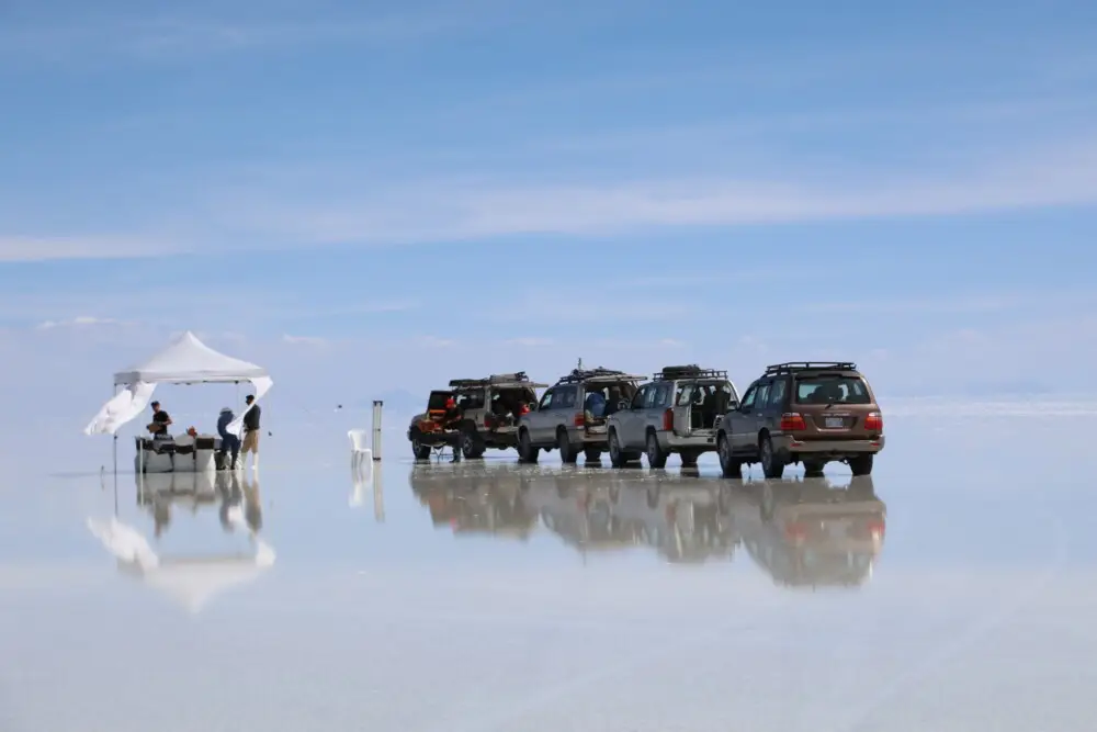 ウユニ塩湖の広大な白い平原に、テントと車が並ぶランチ会場の風景。