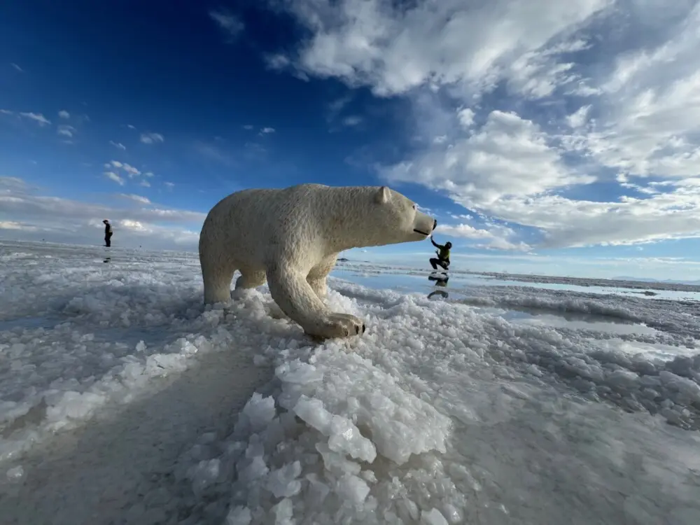 ウユニ塩湖で巨大なシロクマ像と小さな人物が触れ合うトリック写真