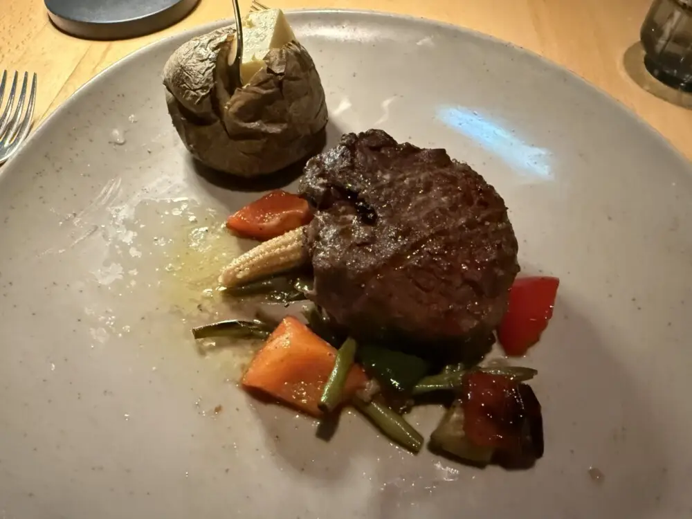肉厚なステーキとベイクドポテト、付け合わせ野菜が並びます。