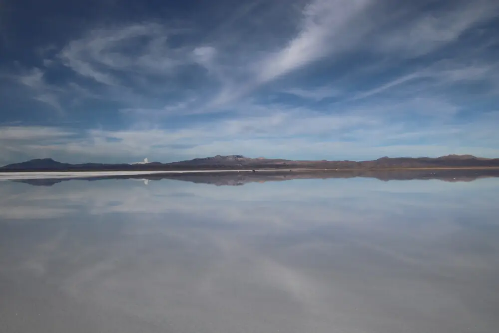 ウユニ塩湖の水面に、空と山々が映り込む様子